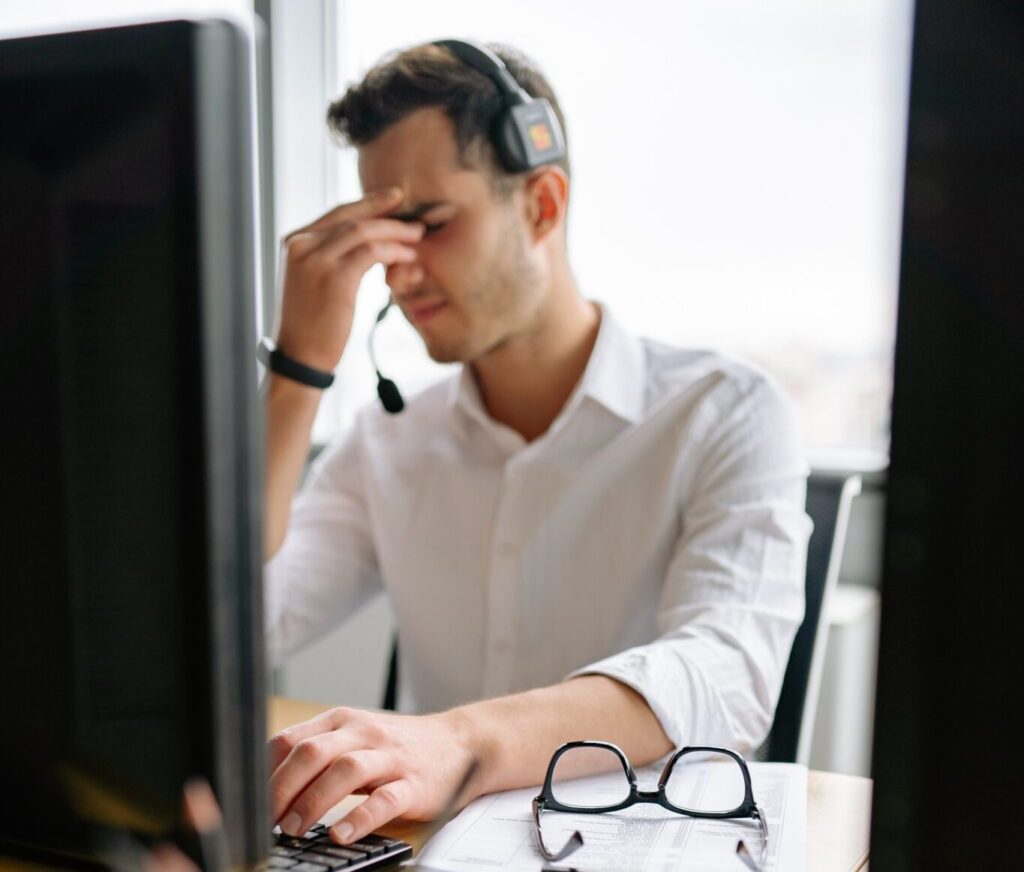 Frustrated customer service agent with their glasses on the desk