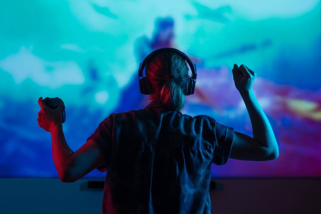 Girl gamer playing games in the headphones on a large screen