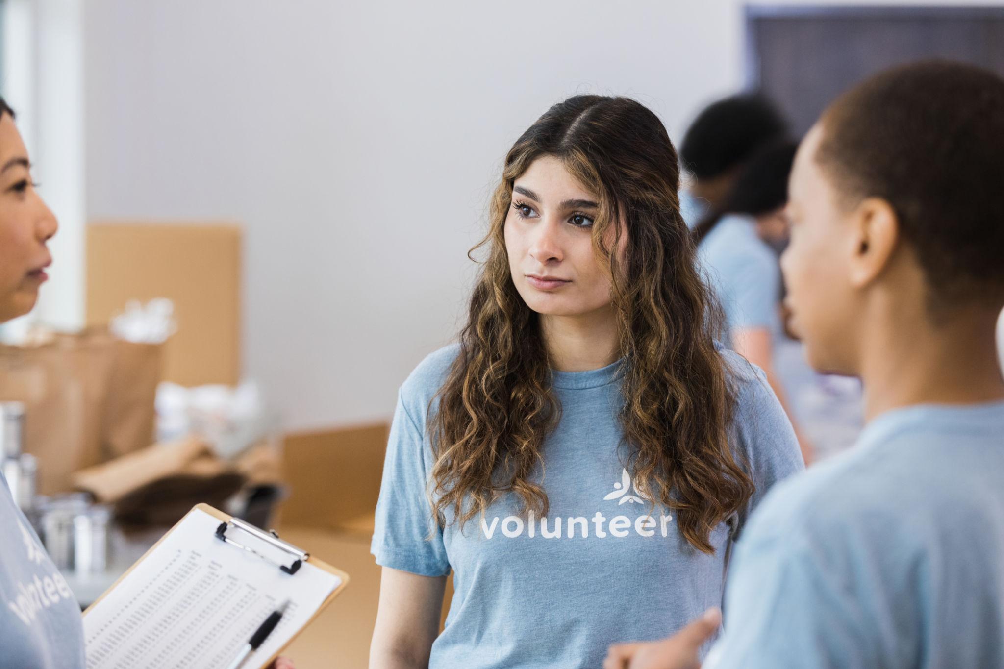 Volunteer coordinator having a calm conversation with volunteers to address conflict and improve teamwork in a nonprofit organization.